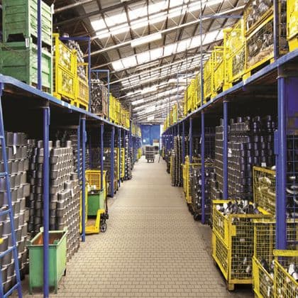 A woman in uniform inspects storage racks in a dimly lit warehouse.